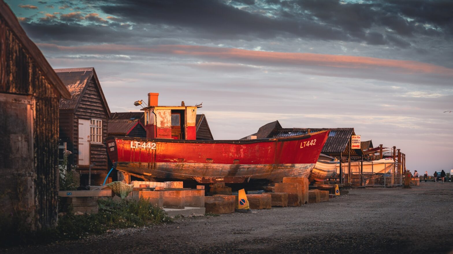 a red boat sitting on top of a wooden dock